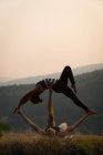 Couple sportif pratiquant l'acro yoga dans un terrain vert luxuriant au moment de dwan — Photo de stock