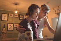 Lesbian couple using laptop at table in living room at home. — Stock Photo