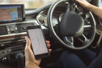 Крупный план женщины-руководителя с помощью мобильного телефона во время вождения автомобиля — стоковое фото