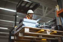 Female worker checking machine part in factory — Stock Photo