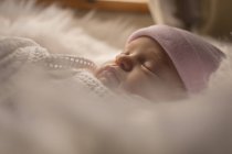 Swaddled newborn baby in hat sleeping on fluffy blanket. — Stock Photo