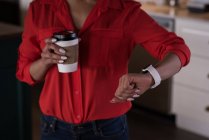 Mittlere Sektion weiblicher Bürokauffrau überprüft Zeit auf Smartwatch im Kreativbüro — Stockfoto