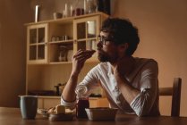 Thoughtful man having breakfast in kitchen at home — Stock Photo