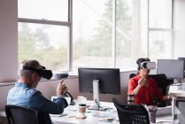 Office colleagues experiencing virtual reality headset at desk in creative office — Stock Photo