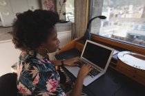 Продумана жінка використовує ноутбук за столом вдома . — стокове фото