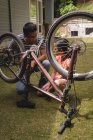 Père et fille interagissent les uns avec les autres tout en réparant le cycle dans le jardin — Photo de stock