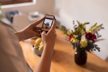 Metà sezione della donna cliccando foto sul cellulare a casa — Foto stock