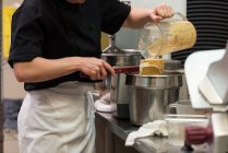 Серединна частина шеф-кухаря заливає мелену суміш в ємності — стокове фото