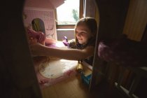 Fille jouer avec poupée maison dans chambre à coucher à la maison — Photo de stock
