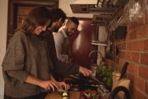 Amigos preparando comida en la cocina en casa - foto de stock