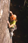 Решительная женщина-альпинистка, взбирающаяся на скалистую гору — стоковое фото