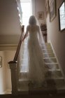Вид сзади на невесту, поднимающуюся по лестнице дома — стоковое фото