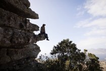 Турист, сидячи на скелі скелі на сонячний день — стокове фото