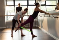 Тренер помогает женщине тренироваться с группой сопротивления в фитнес-студии . — стоковое фото