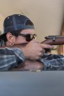 Close-up of man aiming shotgun at target in shooting rangem — Stock Photo