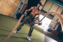 Determined muscular man exercising with rope in the fitness studio — Stock Photo