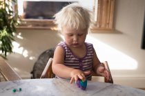 Маленькая девочка играет с глиной дома . — стоковое фото