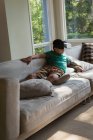 Niño usando auriculares de realidad virtual en la sala de estar en casa - foto de stock
