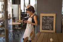 Waitress using mobile phone in coffee shop — Stock Photo