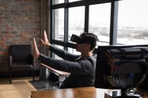 Чоловік виконавчий використовує гарнітуру віртуальної реальності в офісі з розтягнутими руками . — стокове фото