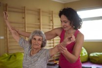 Female therapist assisting senior woman with hand exercise at nursing home — Stock Photo
