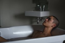 Продуманий молодий чоловік розслабляється у ванній кімнаті — стокове фото