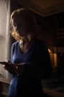 Крупним планом жінка використовує свій мобільний телефон у темній кімнаті — стокове фото