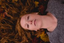 Крупним планом красива жінка лежить на сухому осінньому листі — стокове фото