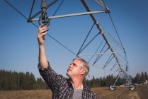 Фермер перевіряє систему зрошення у полі на сонячний день — стокове фото