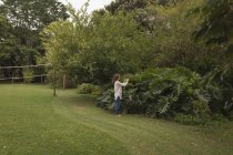 Femme vérifiant les plantes dans le jardin — Photo de stock