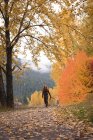 Carefree woman walking in autumn forest with pet dog — Stock Photo