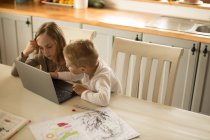 Kinder nutzen Laptop gemeinsam in der heimischen Küche — Stockfoto