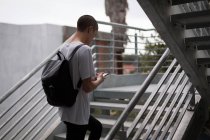 Молодой человек использует мобильный телефон на лестнице — стоковое фото
