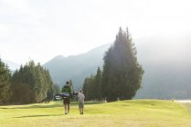 Visão traseira de pai e filho andando com clube de golfe no curso — Fotografia de Stock