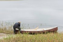 Mann schiebt sein Boot in den Fluss — Stockfoto