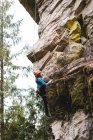 Scalatrice determinata che si arrampica sulla falesia rocciosa — Foto stock