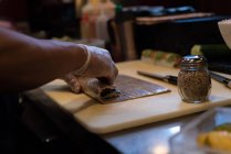 Koch rollt ausgerolltes Sushi auf Schneidebrett — Stockfoto