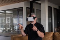 Uomo ufficio esecutivo sperimentando cuffia realtà virtuale sul divano in ufficio creativo — Foto stock