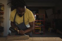 Charpentier sculptant du bois à table en atelier — Photo de stock