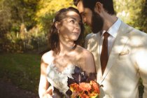 Mariée romantique et marié regardant dans les yeux de l'autre dans le jardin — Photo de stock