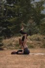 Sportliche Frauen praktizieren an einem sonnigen Tag Akro-Yoga auf offenem Gelände — Stockfoto