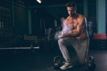 Hombre muscular frotando polvo en las manos en el gimnasio - foto de stock