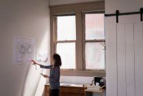 Business woman checking blueprints on wall in office. — Stock Photo