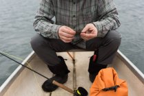 Mann hält Köder in der Hand, während er im Boot sitzt — Stockfoto