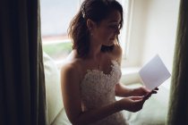 Bonita novia leyendo los votos de boda en casa - foto de stock