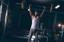 Portrait of muscular man exercising with barbell in the fitness studio — Stock Photo