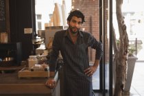 Усміхнений офіціант стоїть за лічильником у кав'ярні — стокове фото