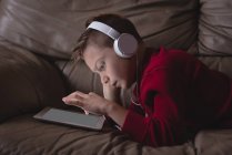Junge nutzt digitales Tablet mit Kopfhörer im heimischen Wohnzimmer — Stockfoto
