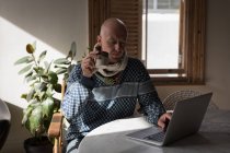 Мужчина пьет кофе дома, пользуясь ноутбуком . — стоковое фото