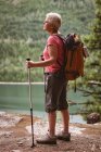 Mature woman with hiking poles standing in the forest — Stock Photo